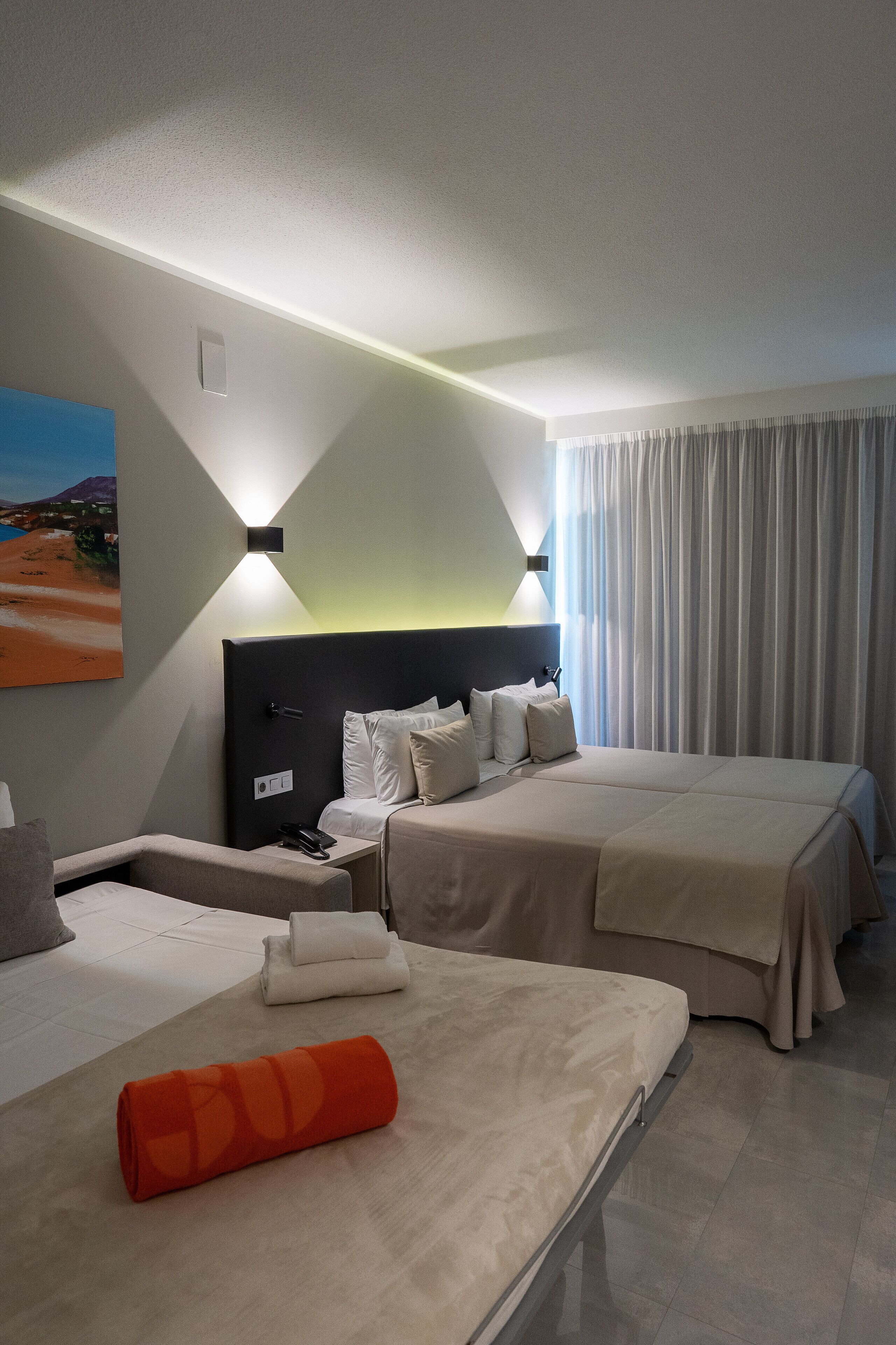 Une chambre d’hôtel avec deux lits, une table de chevet, une lampe et un tableau au mur.
