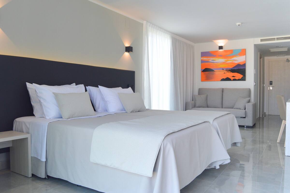 Habitación de hotel con una cama grande, un sofá, un escritorio y un cuadro en la pared.