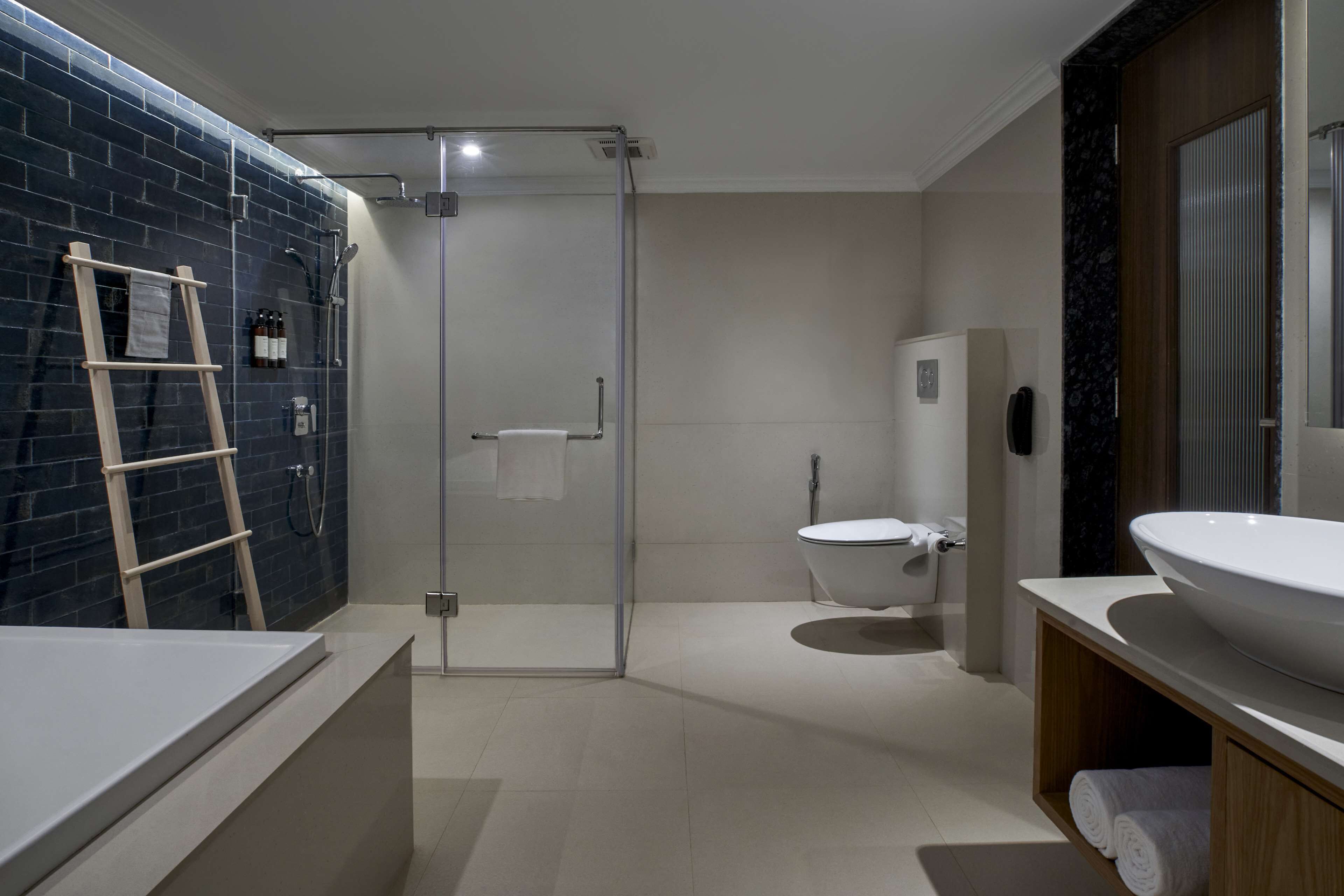A modern bathroom with a glass-enclosed shower, a white toilet, and a large sink.