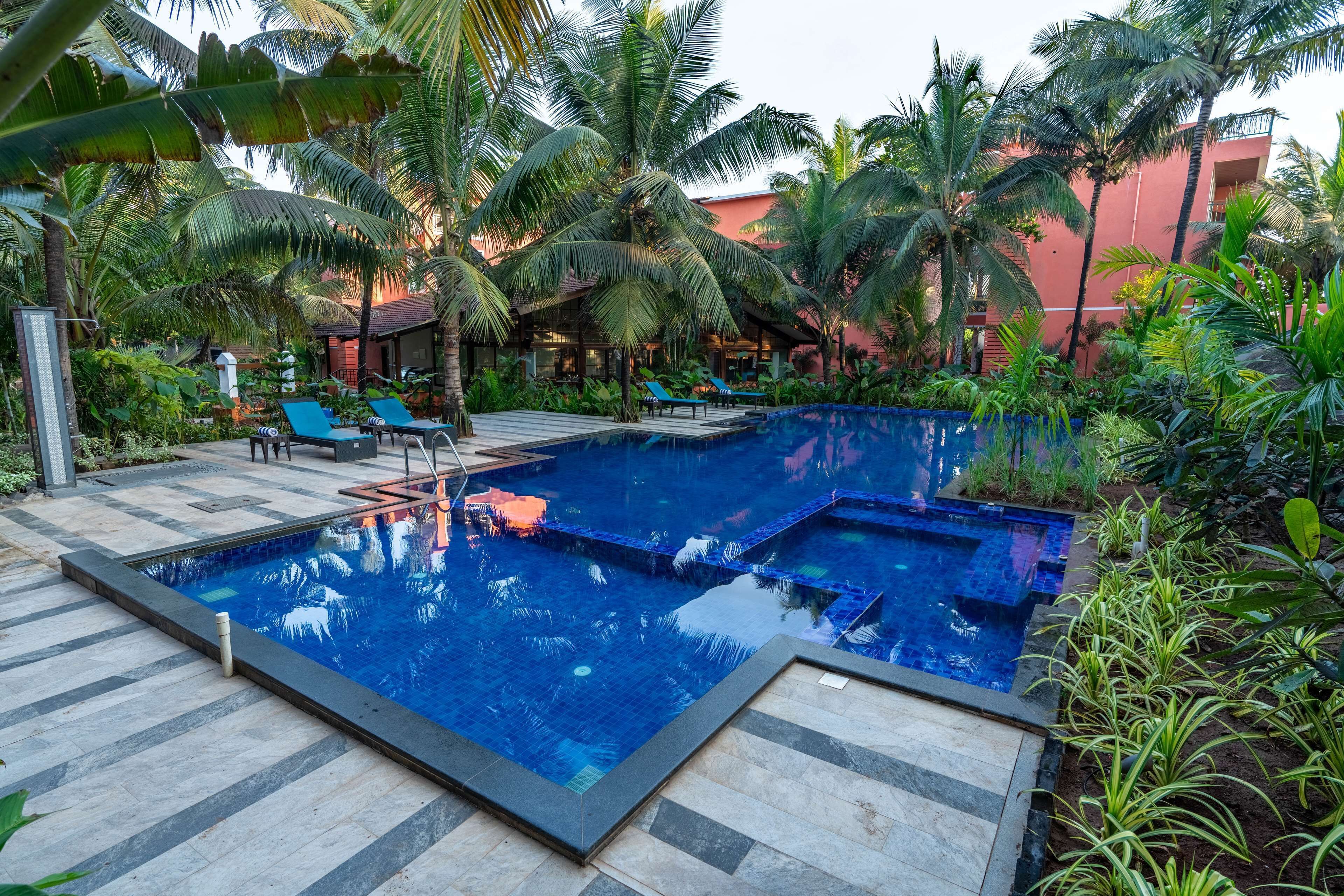 Ein Swimmingpool, umgeben von Palmen und Liegestühlen.