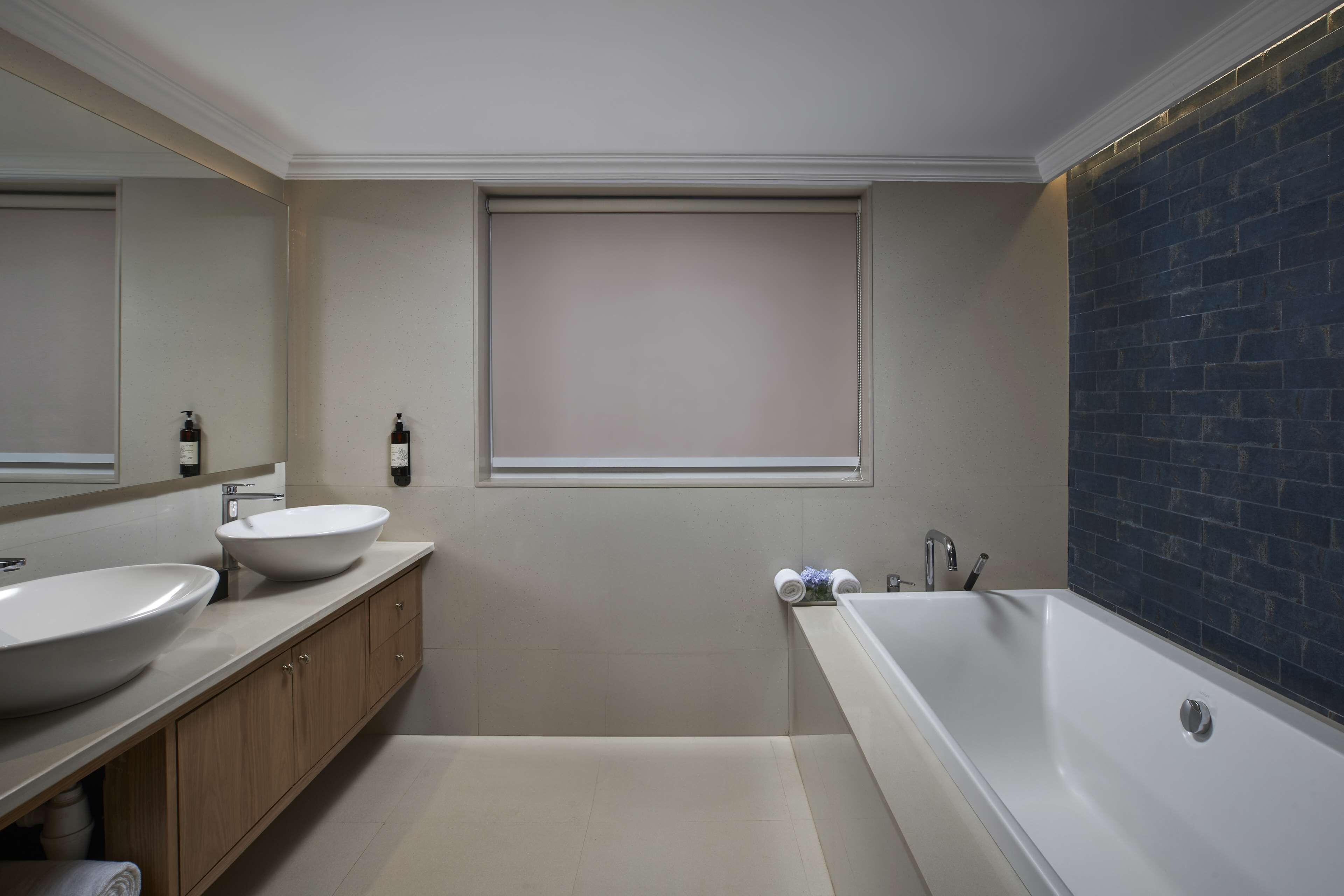 A modern bathroom with two sinks, a bathtub, and a window.