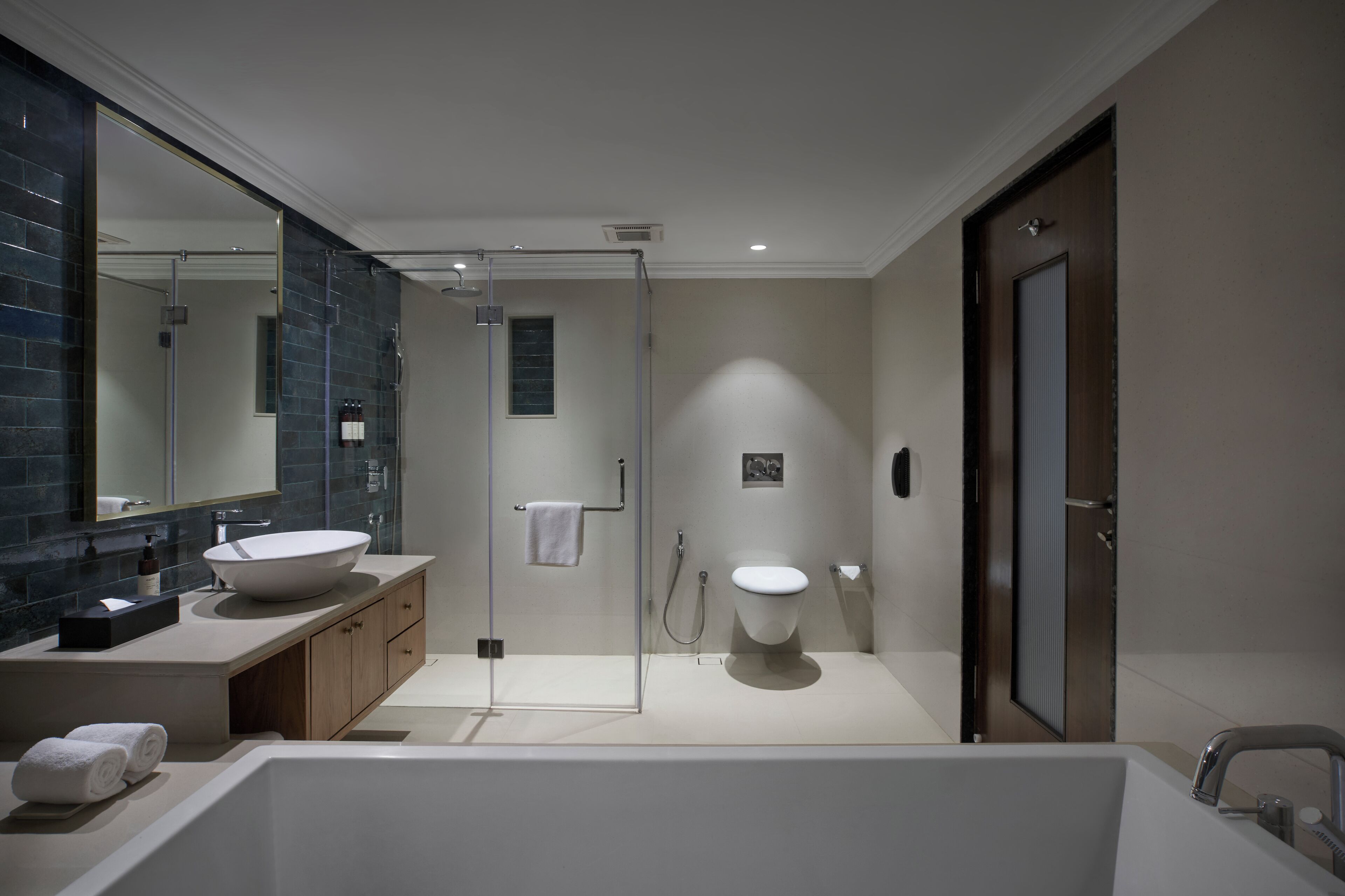 Ein modernes Badezimmer mit einer großen Badewanne, einer gläsernen Duschkabine und einem weißen Waschbecken.