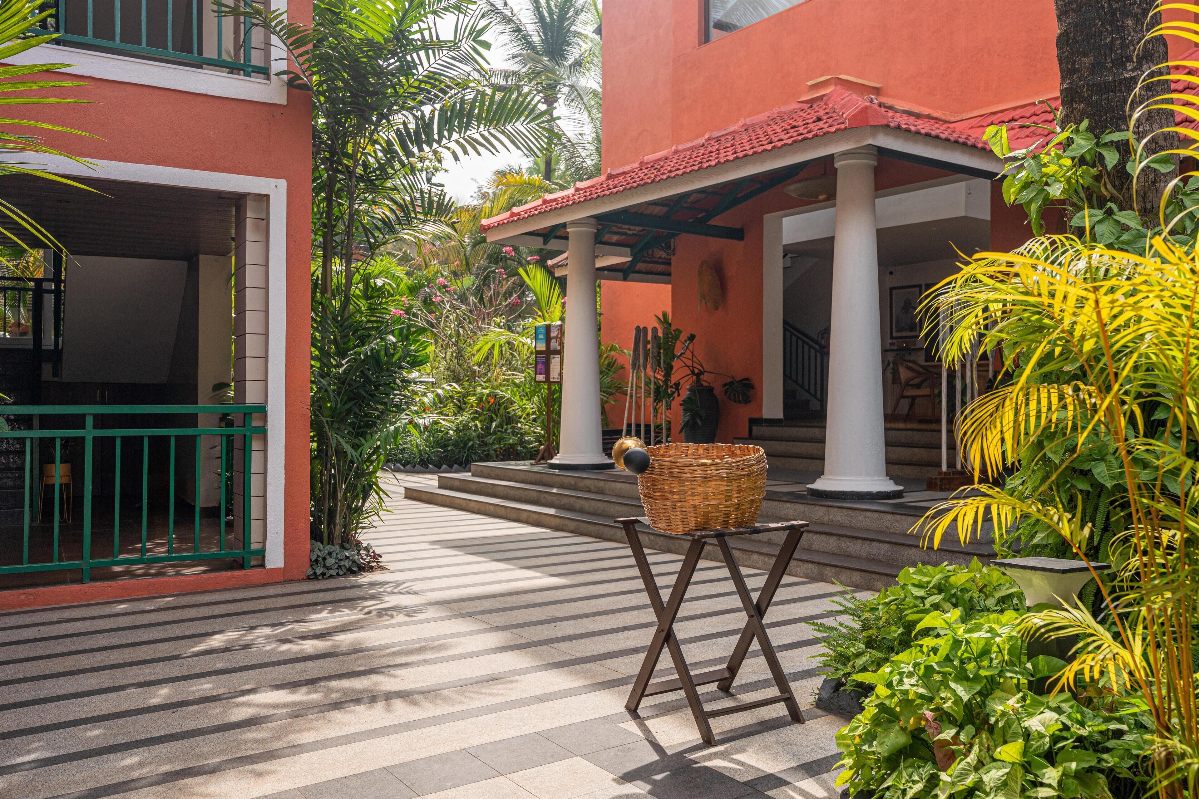 A courtyard with a covered seating area, a wicker basket, and lush greenery.