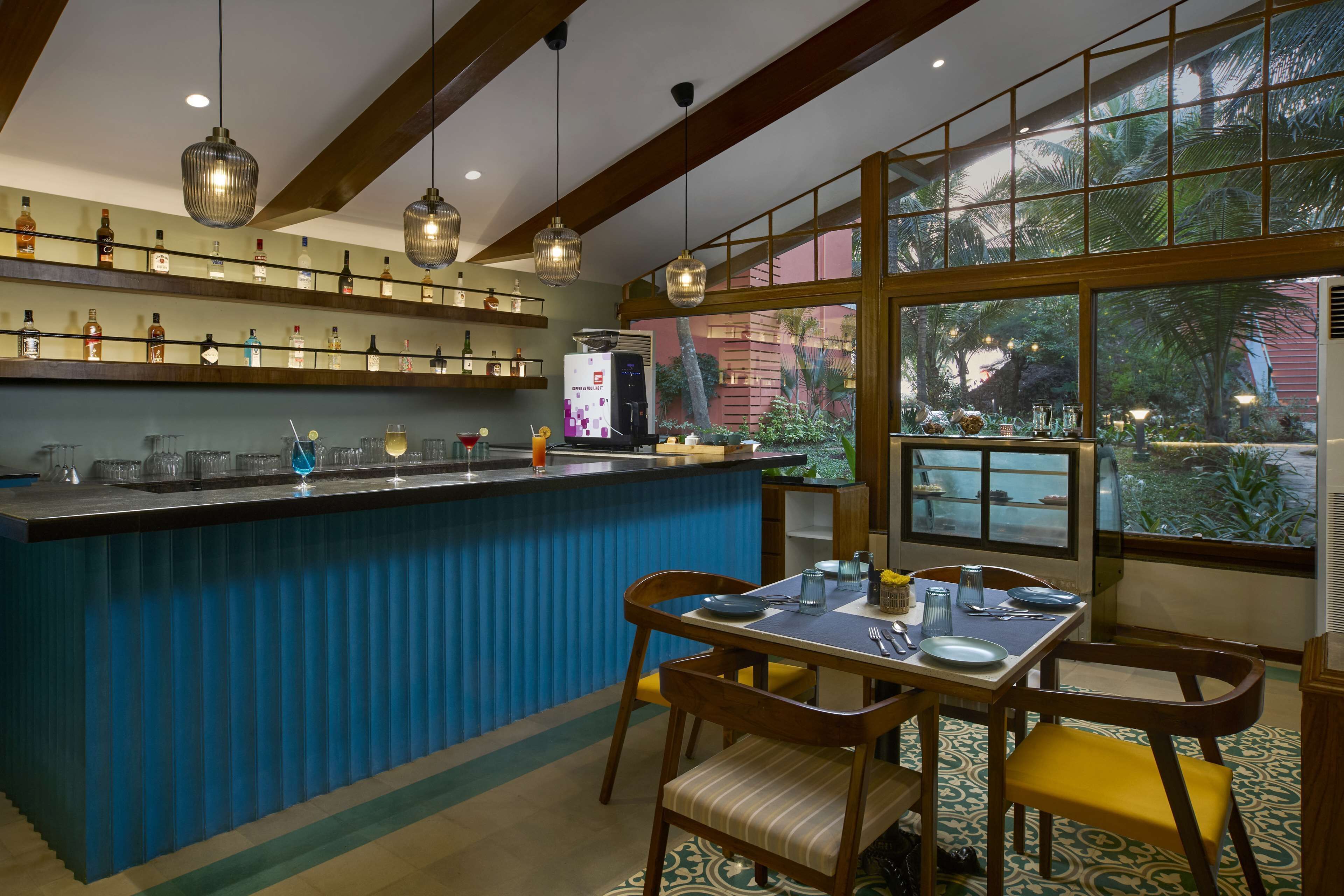 A bar area with shelves of bottles, a counter, and a dining setup with chairs and a table.
