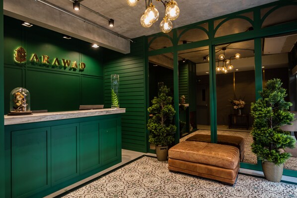 A reception area with a green wall, a reception desk, and a brown leather bench.