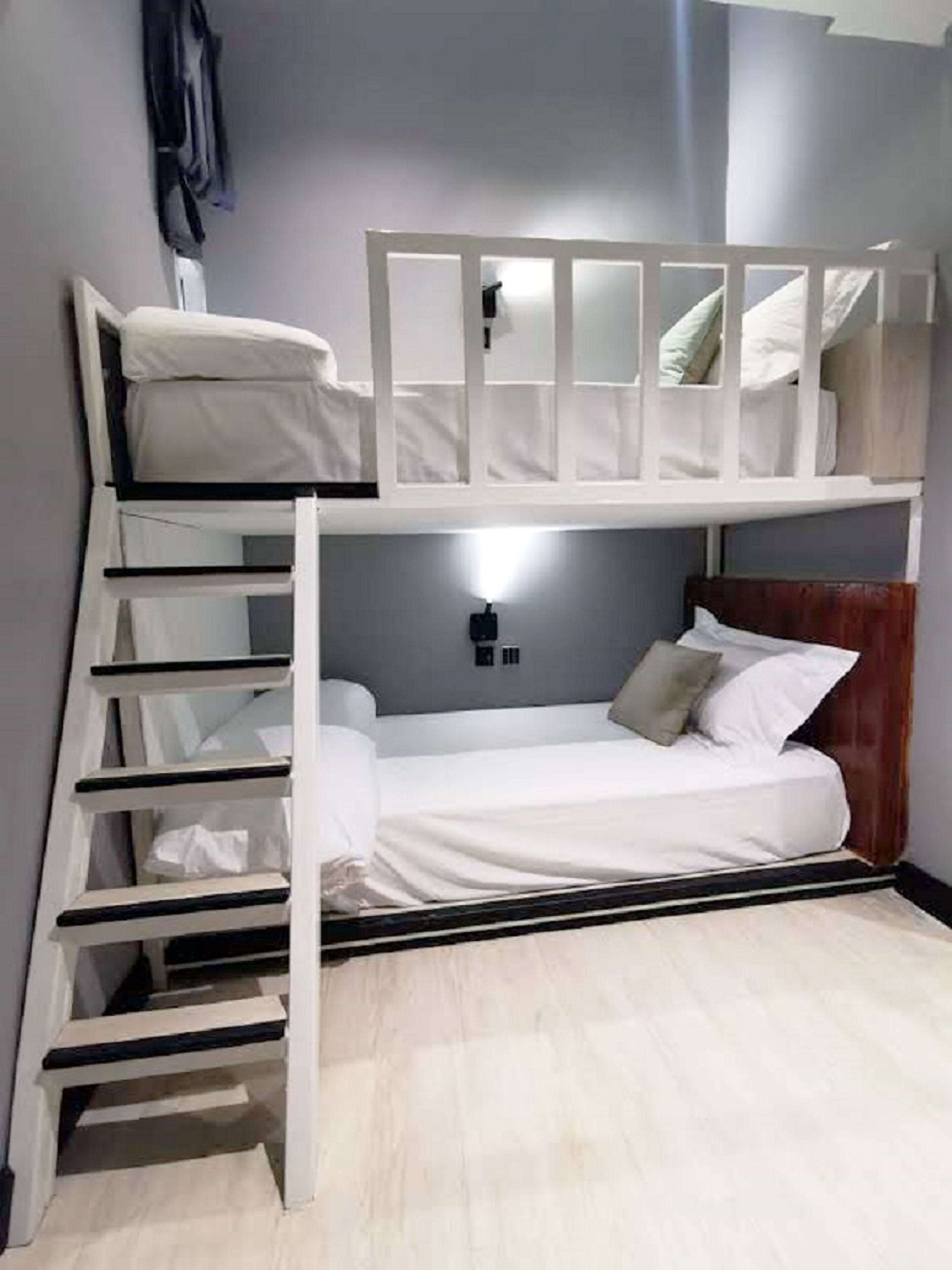Habitación con literas, una mesita de noche y una lámpara fijada a la pared.