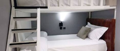 Habitación con literas, una mesita de noche y una lámpara fijada a la pared.