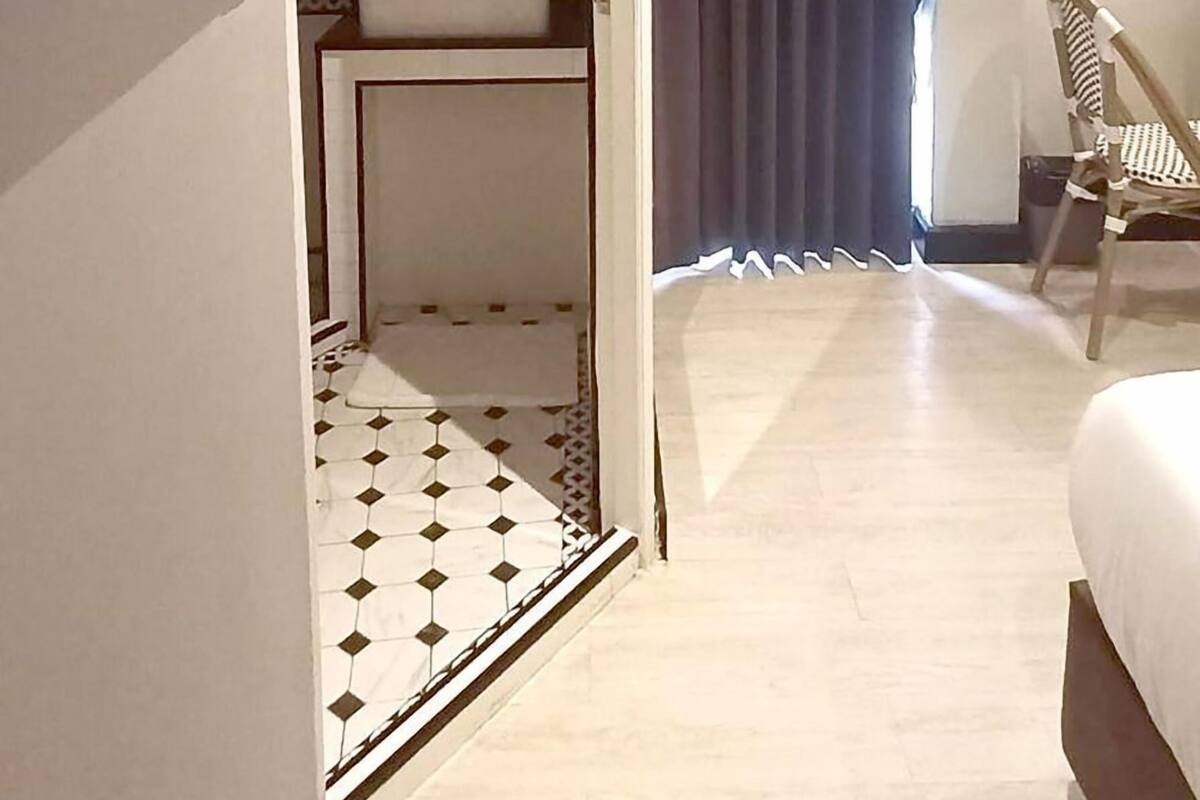 Een hotelkamer met een bed, een bureau, een stoel, een spiegel en een badkamer met wastafel en toilet.