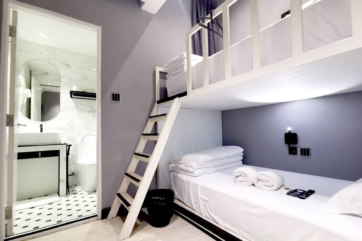 Een moderne hotelkamer met een stapelbed, een badkamer met spiegel en een klein bureau.