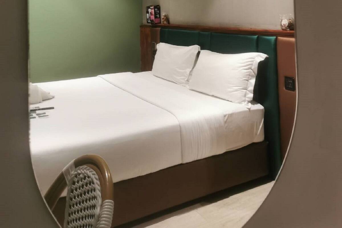 Hotelkamer met een bed, hoofdbord, wandairconditioner en een kleine tafel met stoel.