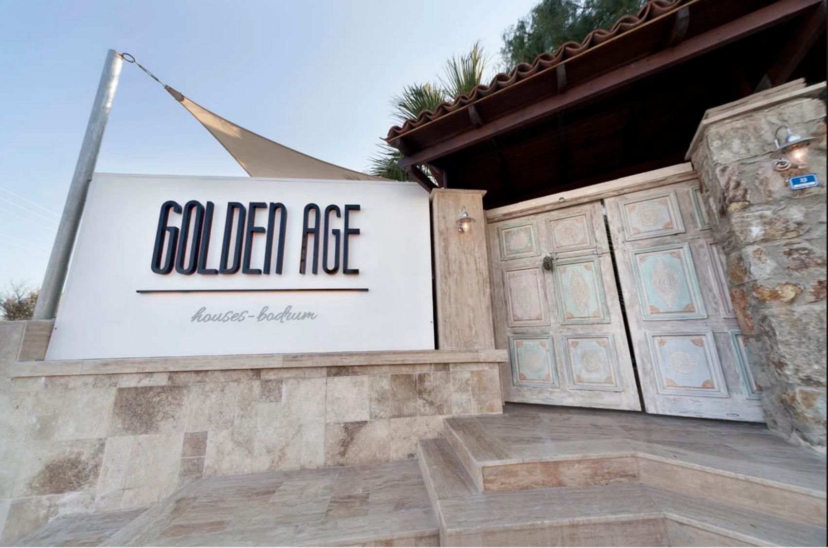 A sign for "Golden Age Houses - Bodrum" with a modern design and a traditional door.