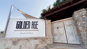 Modernilla tyylillä suunniteltu kyltti, jossa lukee ”Golden Age Houses – Bodrum”, ja perinteinen ovi.