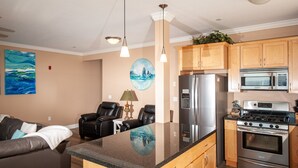 Une cuisine moderne dotée d’un îlot central, d’appareils électroménagers en acier inoxydable et de meubles de rangement en bois.