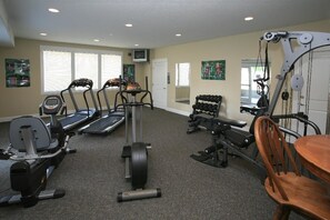 A home gym with treadmills, a stationary bike, a rowing machine, dumbbells, and a weight bench.