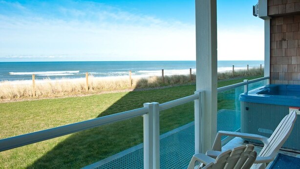 Un balcon avec vue sur l’océan, un jacuzzi et deux chaises.