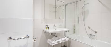 A modern bathroom with a glass-enclosed shower, a white sink with a mirror above it, and a towel rack.