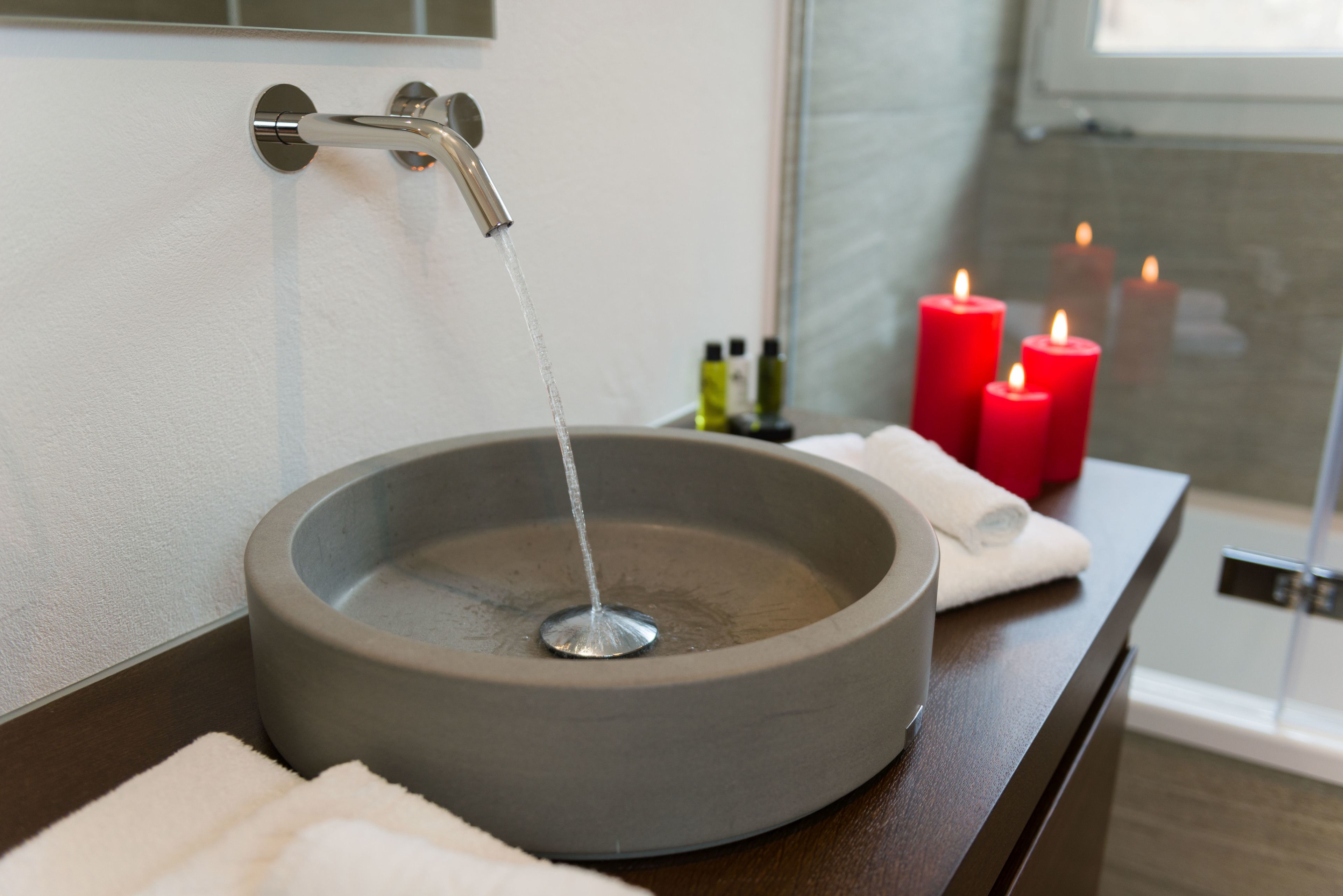 Een badkamer met een rond wastafel, een kraan en kaarsen op het aanrecht.