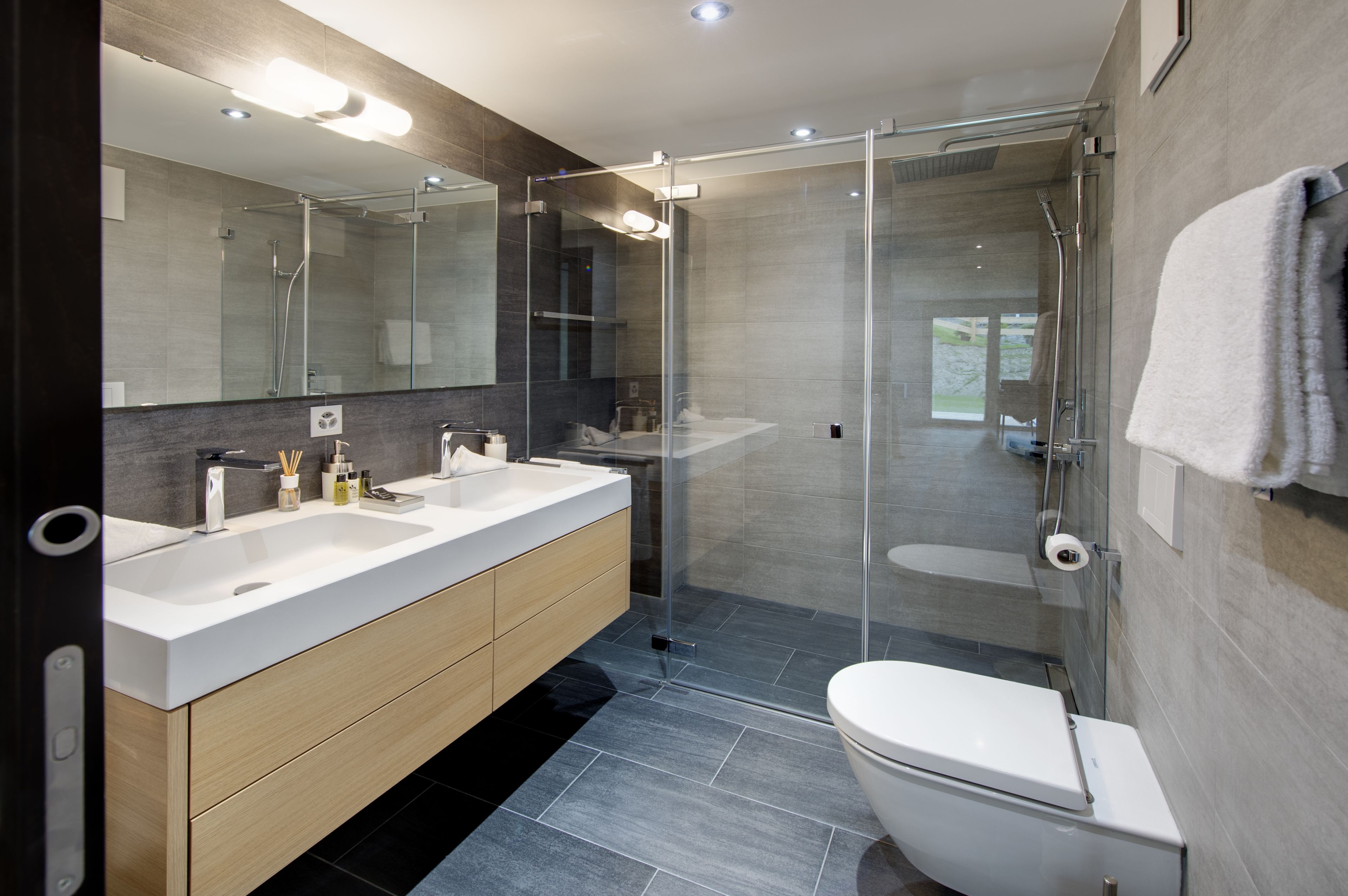 Une salle de bain moderne avec une douche à parois de verre, un lavabo blanc et des toilettes.