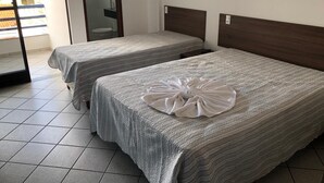 A hotel room with two beds, a bathroom with a glass door, and a view of a building outside. - Hotel Kalilândia (Feira de Santana)