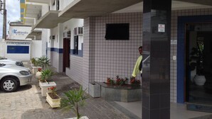A building with a tiled exterior, a parked car, and a sign for 'Estacionamento Para'. - Hotel Kalilândia (Feira de Santana)