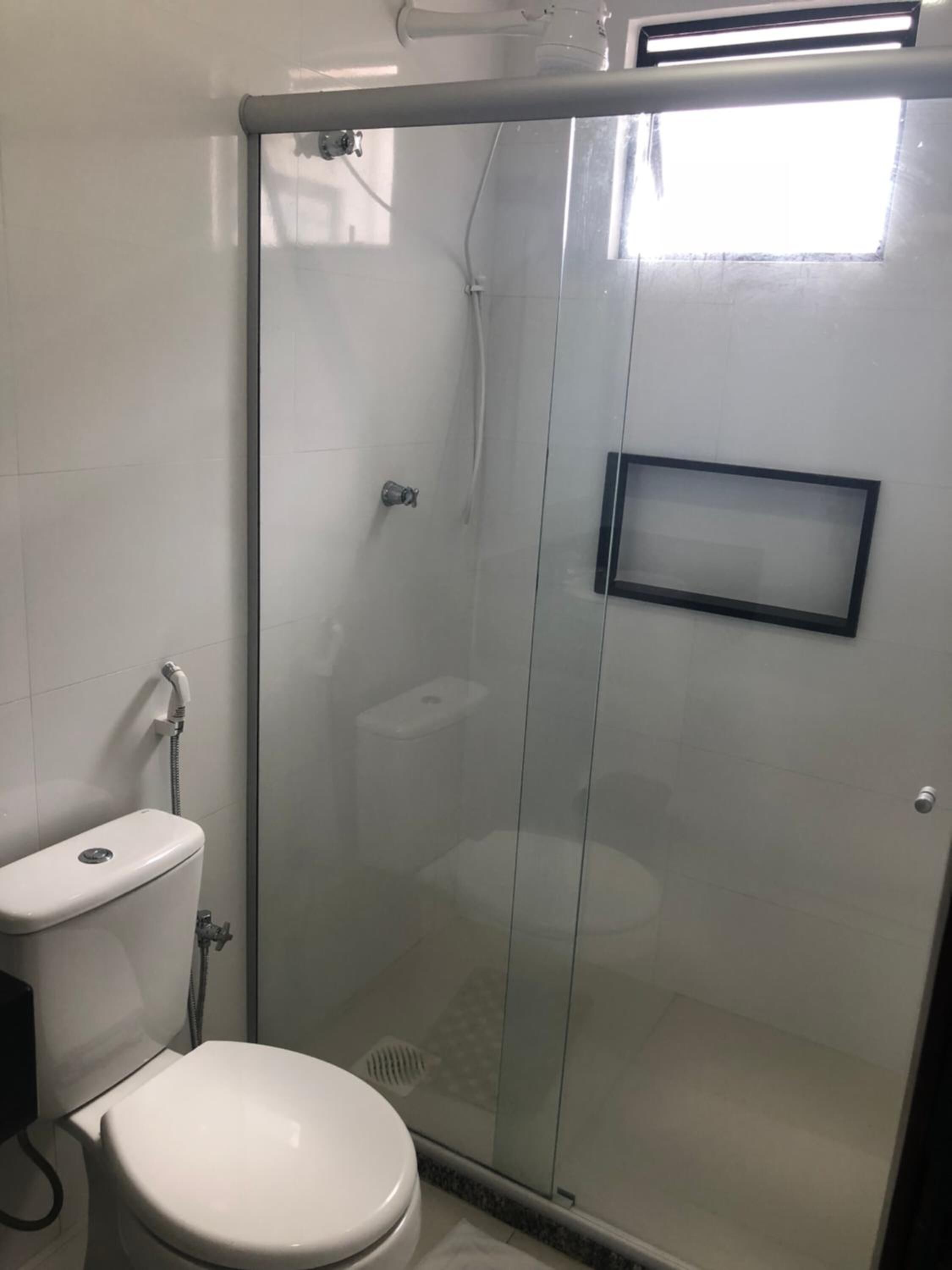 Un baño con ducha de vidrio, inodoro y lavamanos.