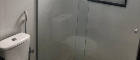 Un baño con ducha de vidrio, inodoro y lavamanos.
