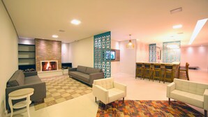 A modern living room with a fireplace, a sofa, a coffee table, and a patterned rug. - Moinho Itália Hotel (Campos do Jordão)
