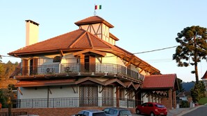 A two-story house with a balcony, a chimney, and a flag. - Moinho Itália Hotel (Campos do Jordão)
