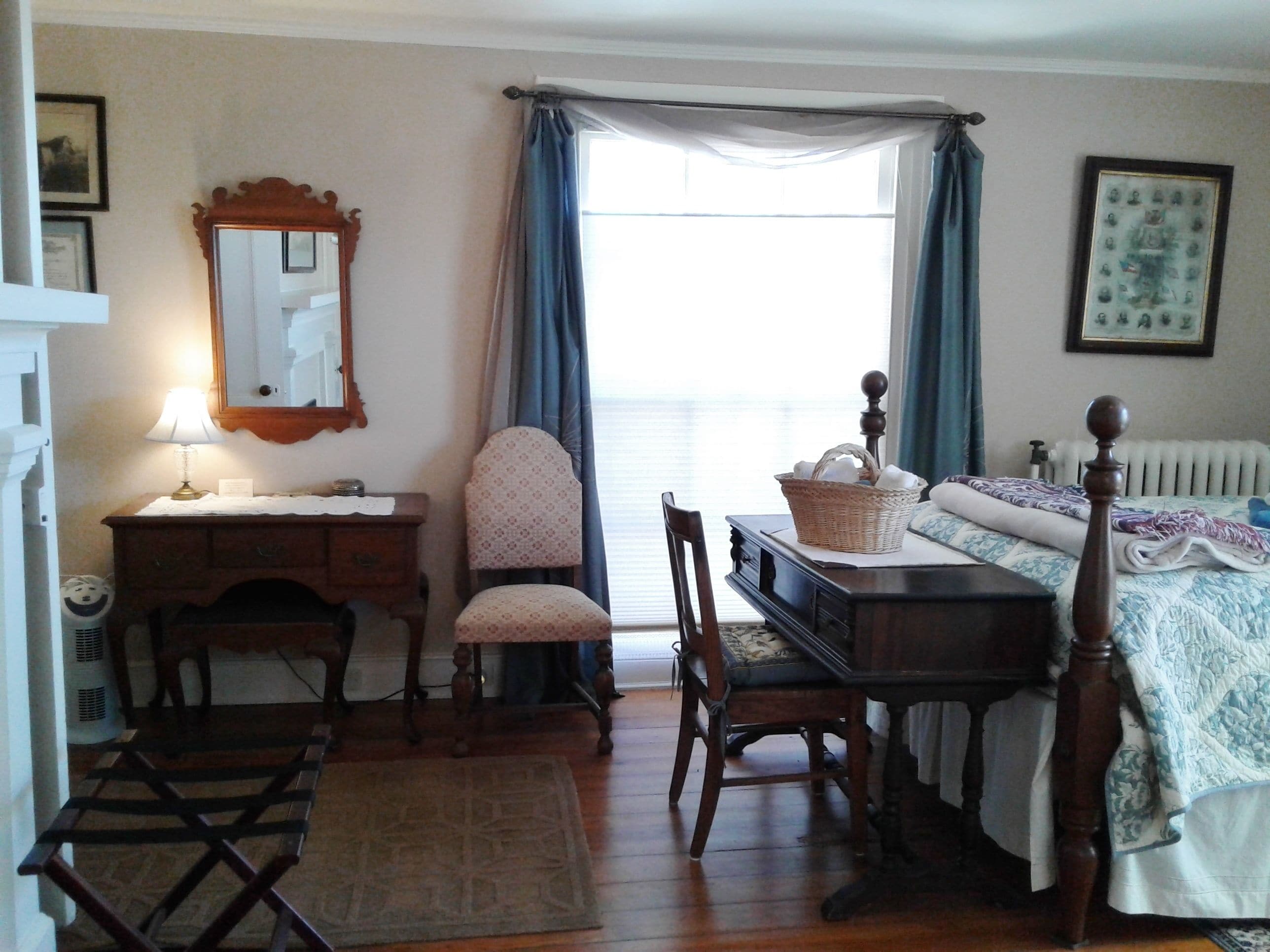 Une chambre à coucher avec un lit en bois, un bureau avec une lampe, une chaise, une commode, une fenêtre avec des rideaux et un radiateur.