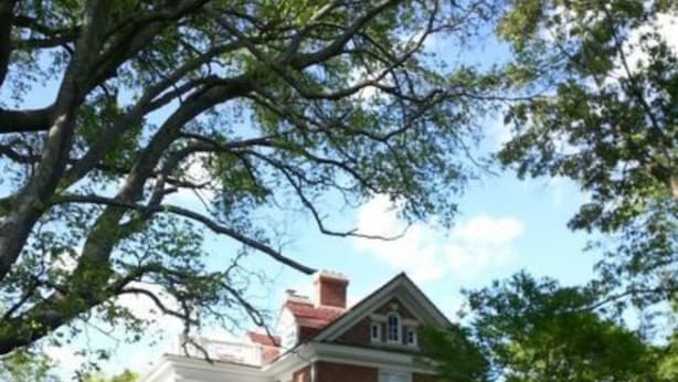 A large, two-story building with a wrap-around porch and a garden in front. - The Boxley Place Inn (Louisa)
