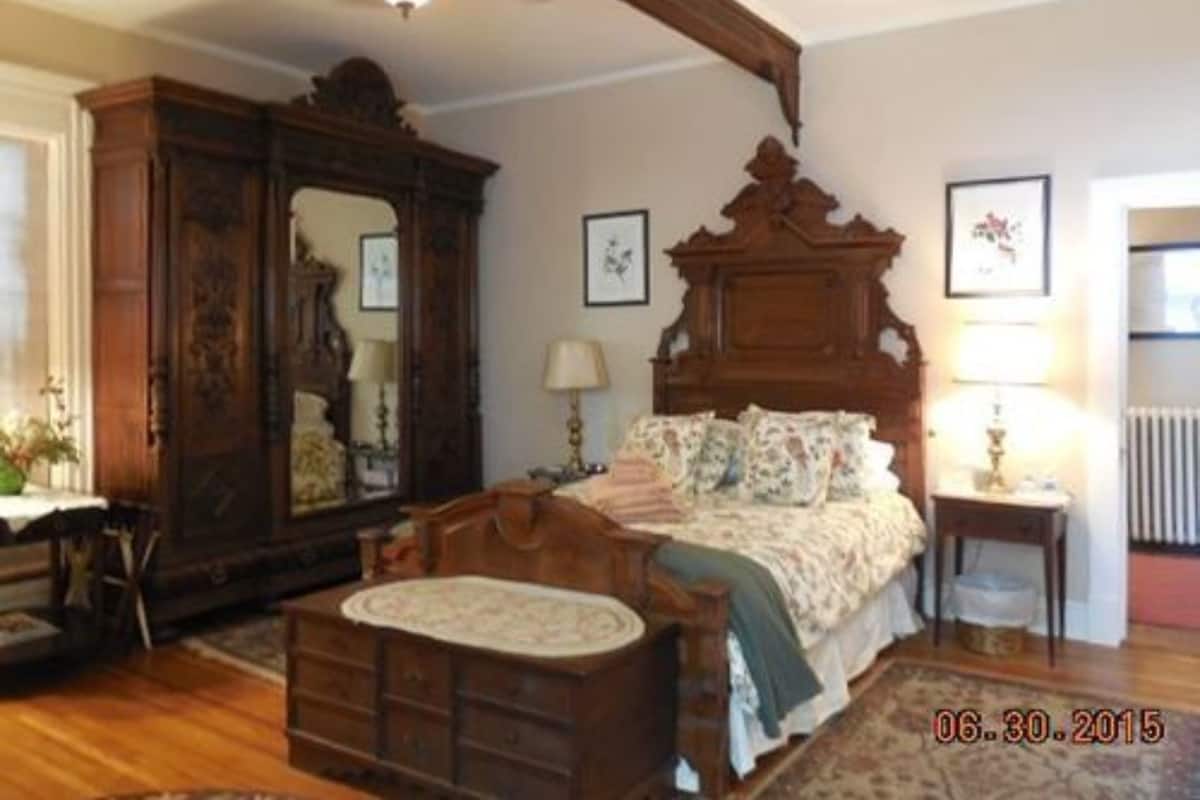 A bedroom with a wooden bed, a dresser, a mirror, and a nightstand.