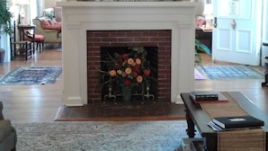 A spacious living room with a fireplace, a chandelier, and a large floral painting above it. - The Boxley Place Inn (Louisa)