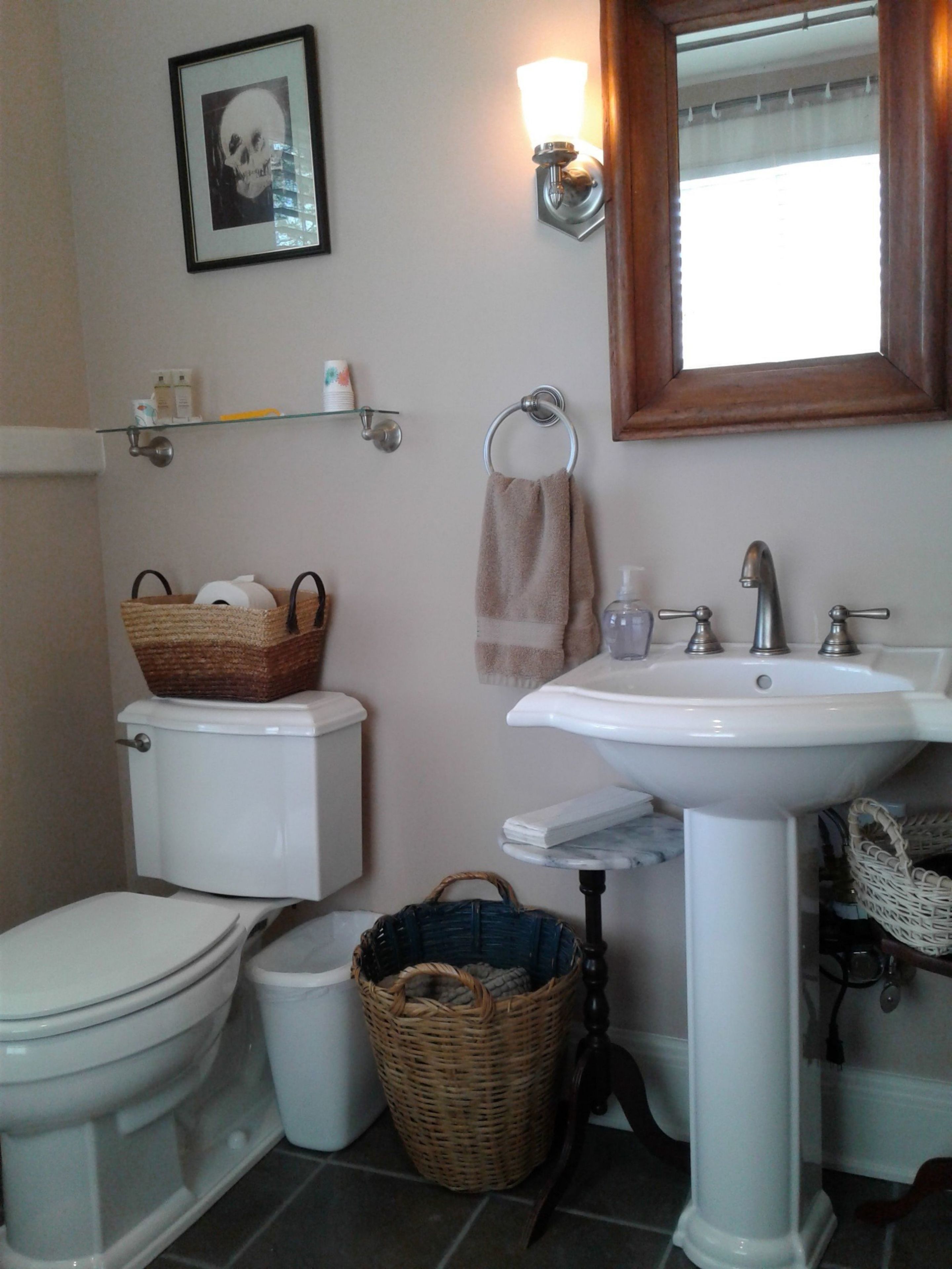 Une salle de bain avec des toilettes, un lavabo et un panier posé sur les toilettes.