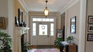 A hallway with a fireplace, a chandelier, and framed pictures on the walls. - The Boxley Place Inn (Louisa)