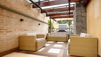 A covered patio area with wicker furniture, a stone wall, and a brick wall.