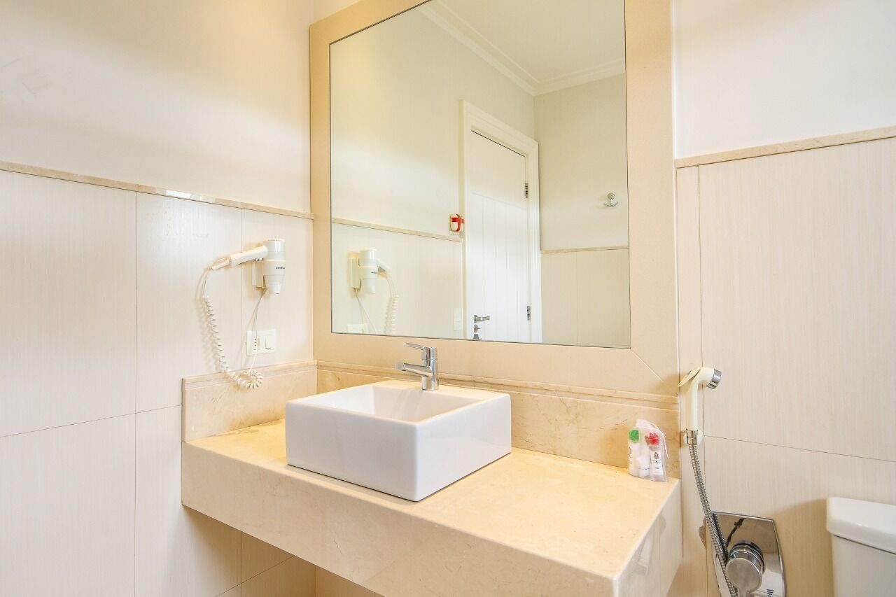 A bathroom with a white sink, a mirror, a toilet, and a shower.