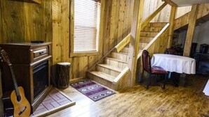 Un intérieur en bois avec un escalier, une table à manger et une guitare.