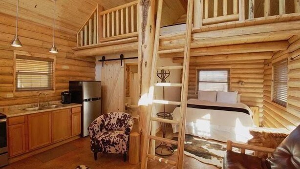 L’intérieur d’une cabane en rondins comprend une cuisine, un coin repas, une chambre et une mezzanine.