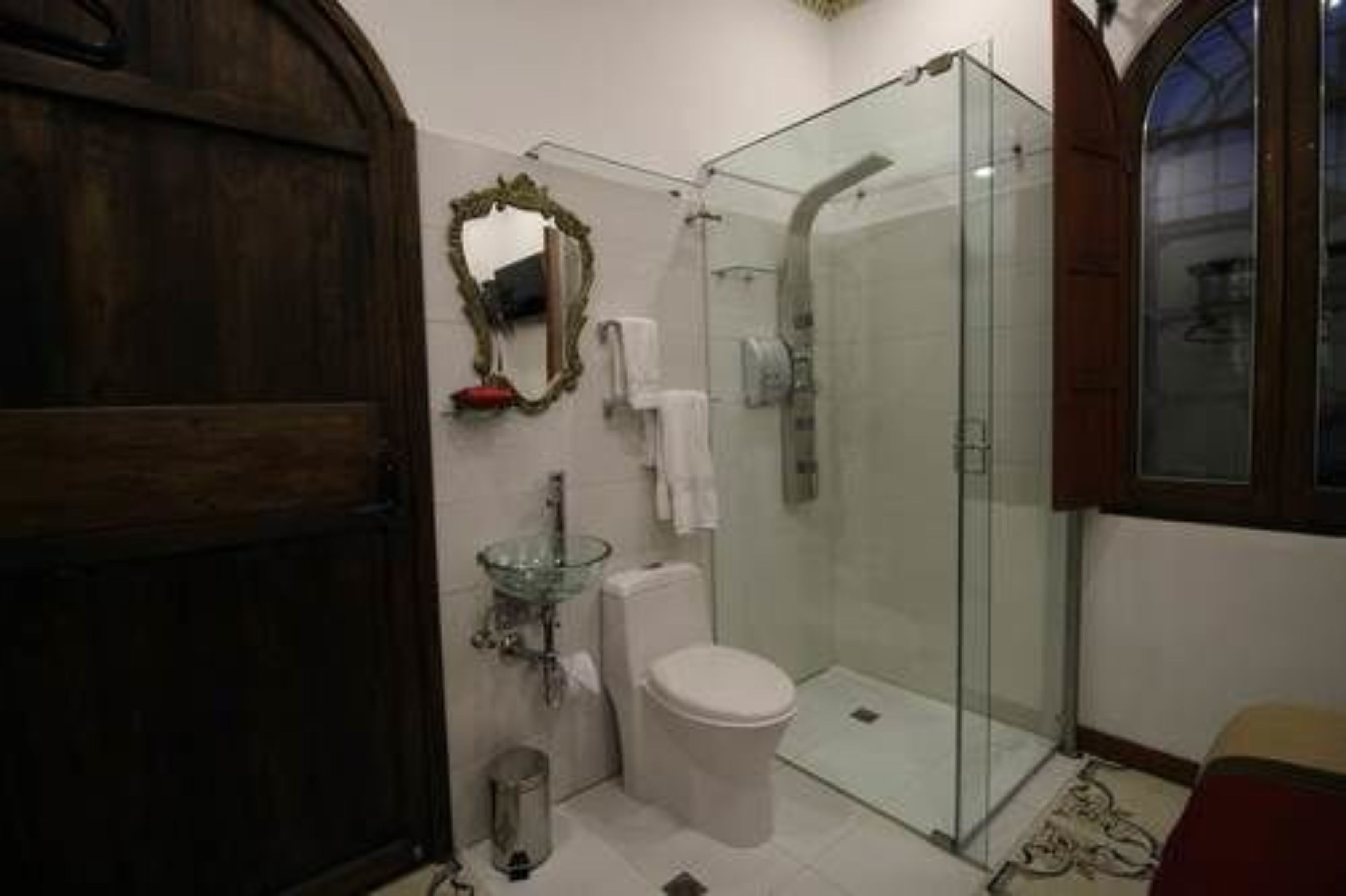 A bathroom with a glass shower enclosure, a white toilet, and a glass sink.
