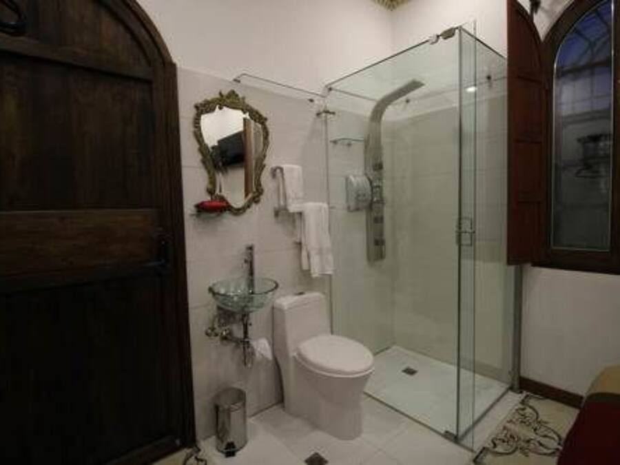 A bathroom with a glass shower enclosure, a white toilet, and a glass sink.
