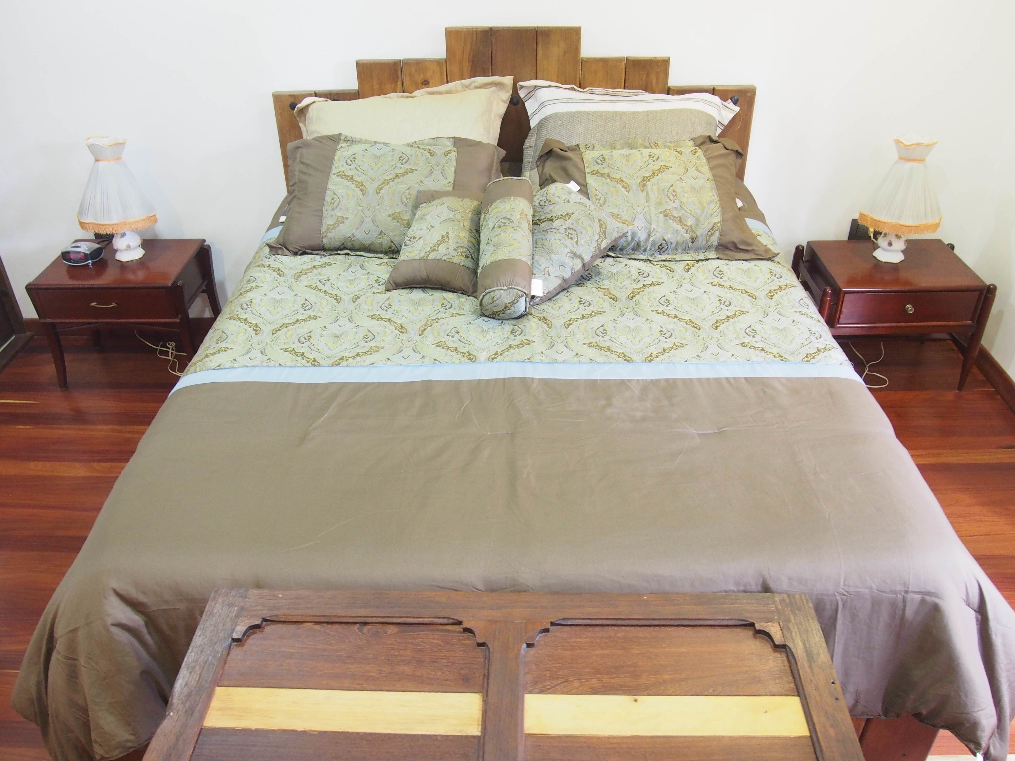 A neatly made bed with patterned bedding and pillows, wooden headboard, and two bedside tables with lamps.