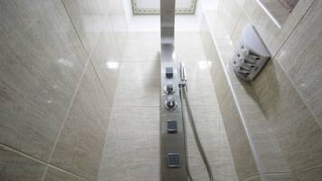 A modern bathroom with a shower, a hand dryer, and a towel dispenser.