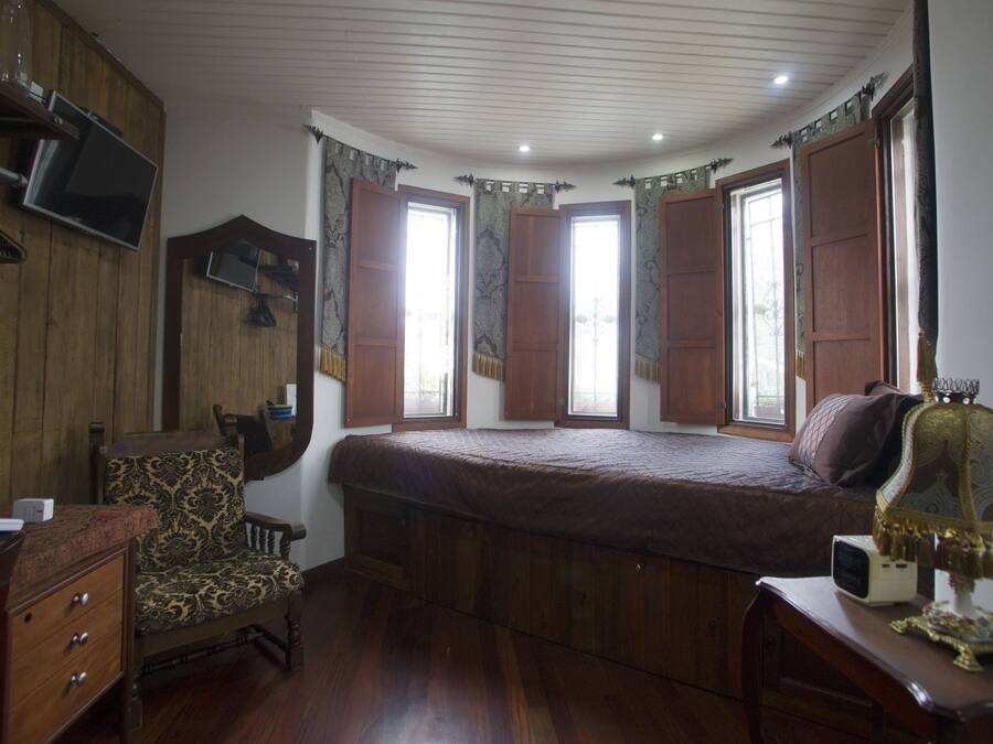 Ein Schlafzimmer mit einem großen Bett, Holzmöbeln, einem an der Wand montierten Fernseher und einer Lampe auf einem Nachttisch.