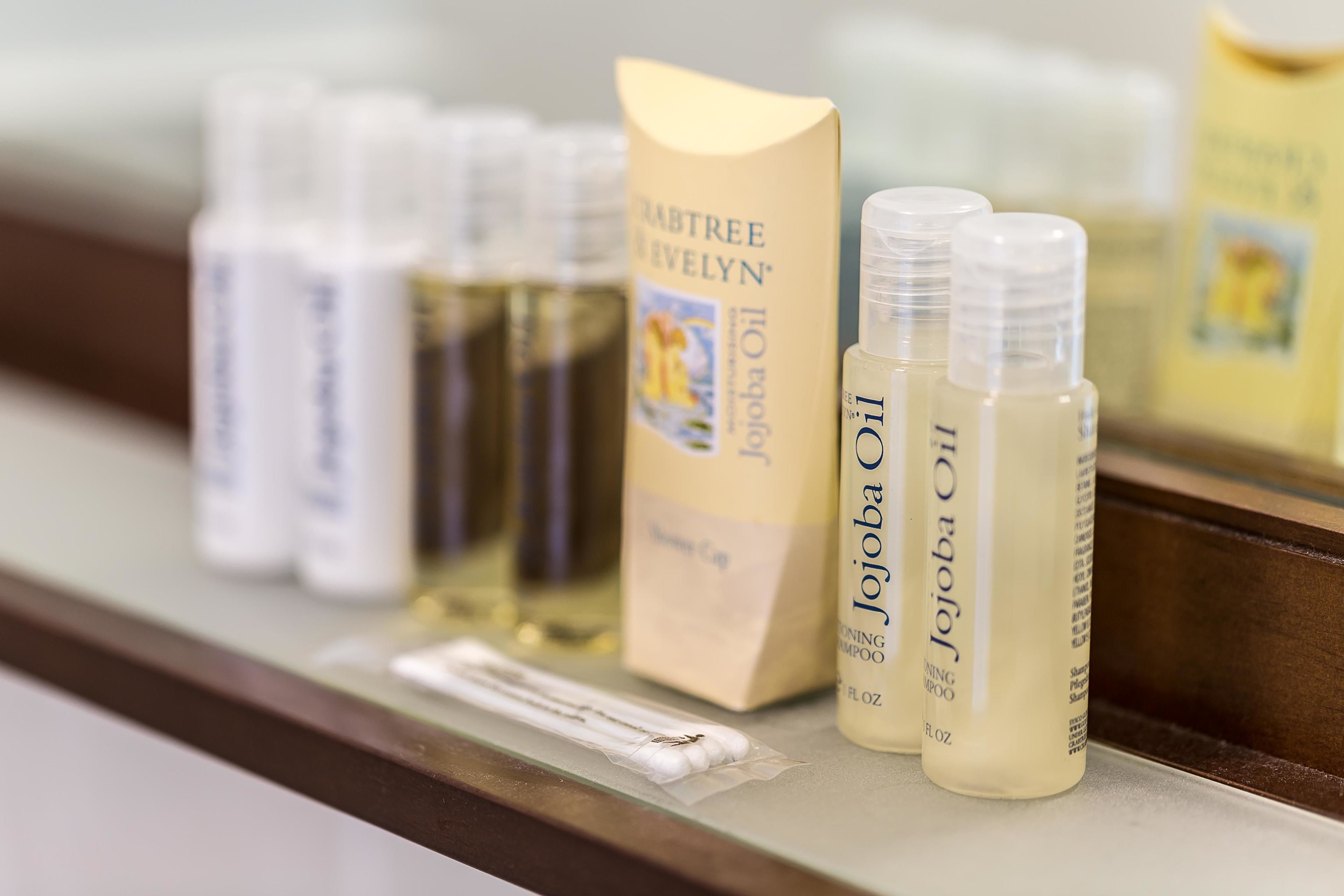 A shelf with various hair care products including a box of 'Jojoba Oil Shampoo' and several bottles of 'Jojoba Oil'.