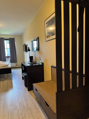 A bedroom with a bed, a desk, a chair, a mirror, and a window with curtains.