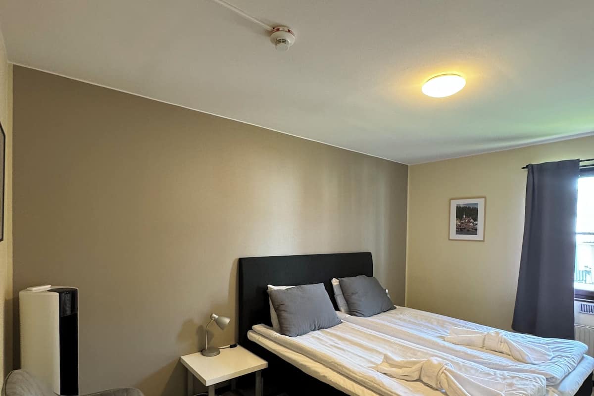 Una habitación de hotel con una cama, una silla, una mesita de noche y un radiador.