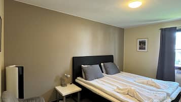 Una habitación de hotel con una cama, una silla, una mesita de noche y un radiador.