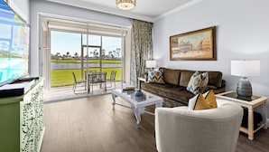 A spacious living room with a glass door leading to a balcony, a comfortable sofa, a coffee table, and a painting on the wall.