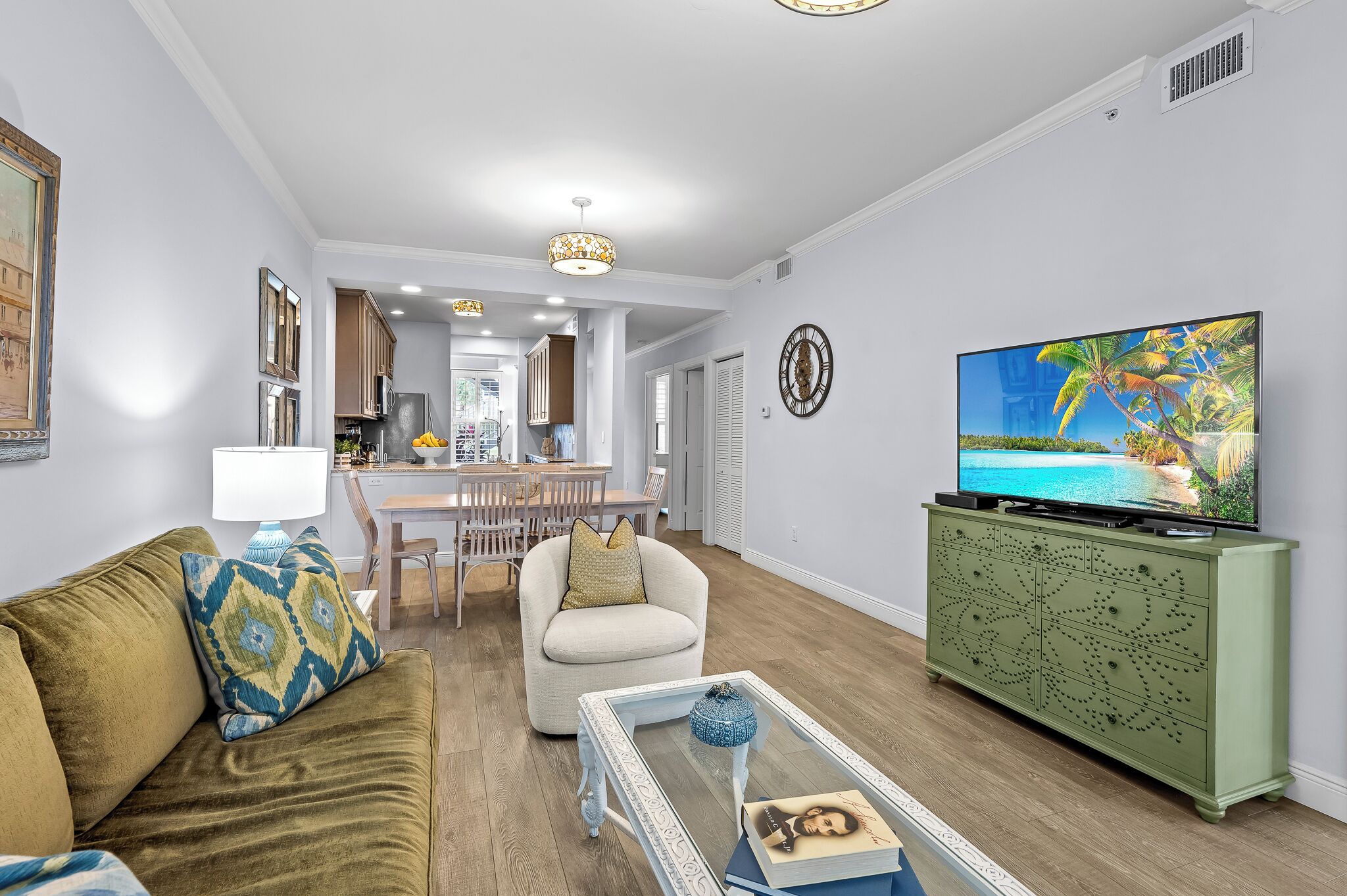 A modern living room with a sofa, armchair, coffee table, and a TV on a cabinet.
