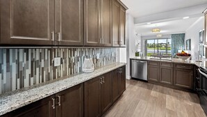 A modern kitchen with dark wood cabinets, a granite countertop, and a mosaic tile backsplash.